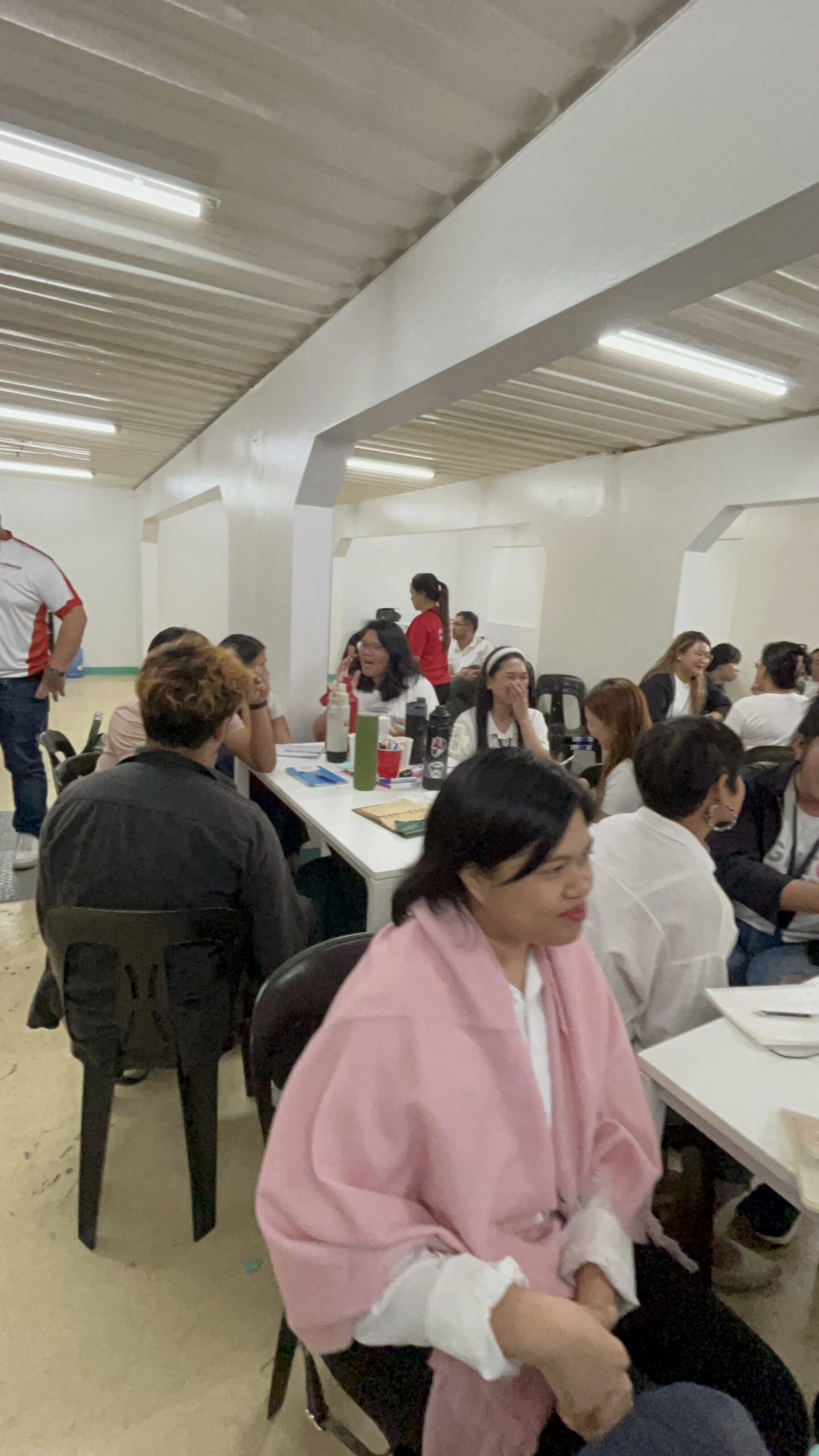 A group of volunteers organized in an assembly line packing and stacking hundreds of identical cardboard relief boxes in a staging area.